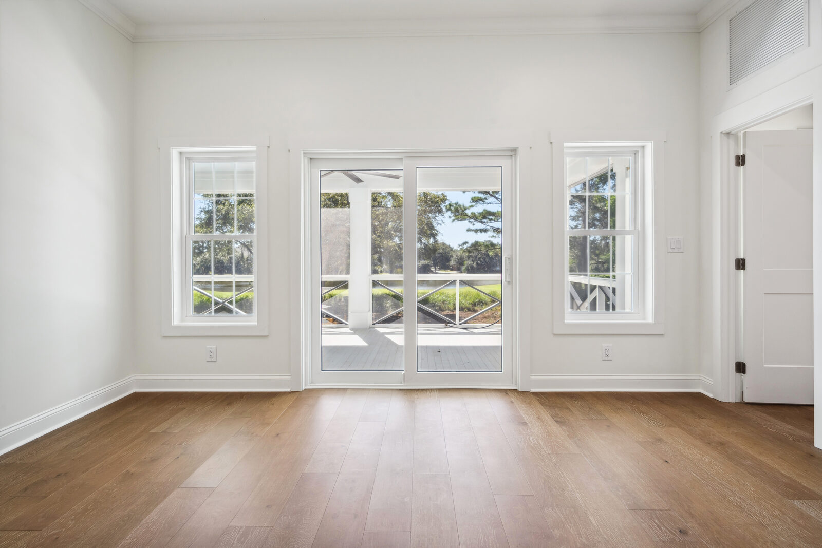 Sunlit empty room with refinished hardwood flooring