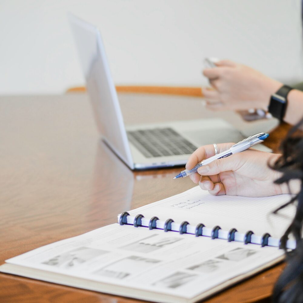 Designer reviewing flooring plans with laptop and notebook
