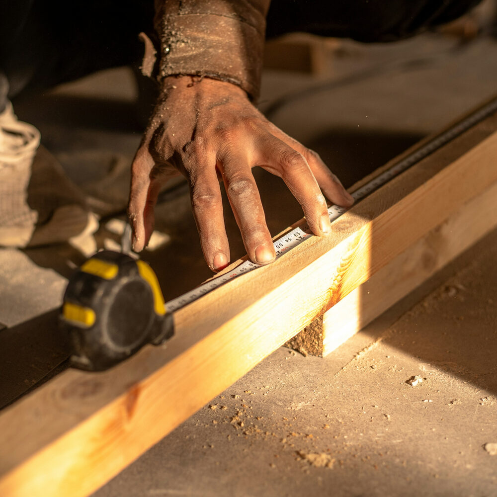 Installer measuring hardwood plank with tape